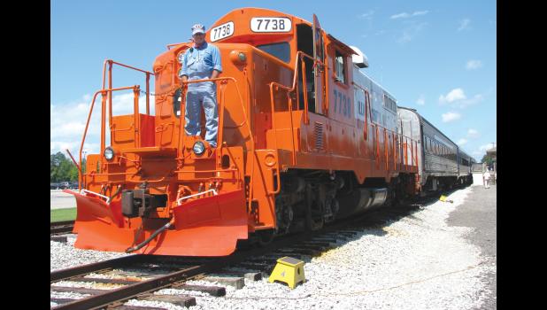 Engineer Mike Walker stands on the front of a restored, orange and white Illinois Central Gulf locomotive, number 7738. Walker, a volunteer, is from Lawrenceburg, Kentucky.